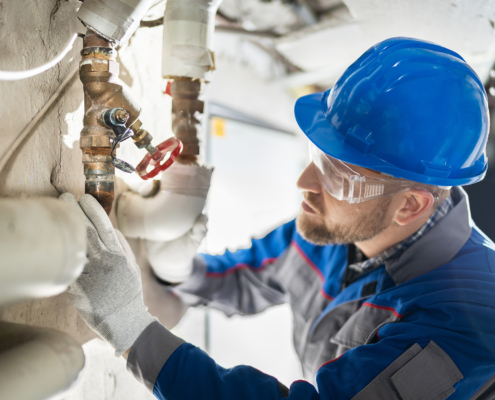 Side view of a plumber inspecting a valve