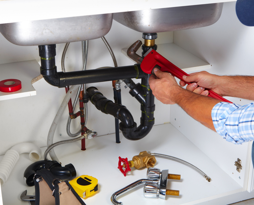 Side view of a plumber working under a kitchen sink