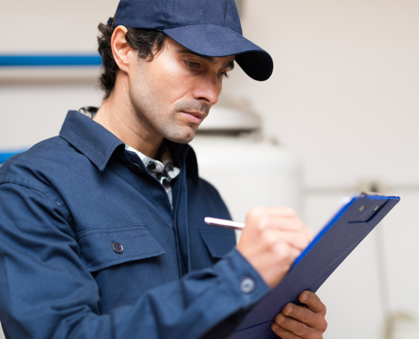 Side view of plumber writing something on clipboard