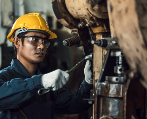 Side view of handsome maintenance man in industrial setting wearing hard hat